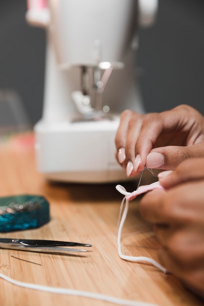 Free Photo tailor using a needle to make a fabric mask and blurred sewing machine