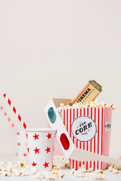 Free photo takeaway drinking glass with straw; 3d glasses; cinema tickets and popcorn box against white backdrop