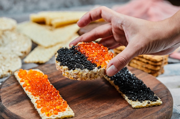 Taking a cracker sandwich with red and black caviar. 