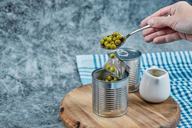 Taking green pea beans ouf of a metallic can. 