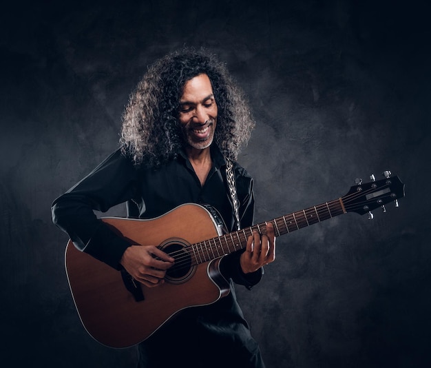 Free photo talented musician is performing with his guitar at dark studio.