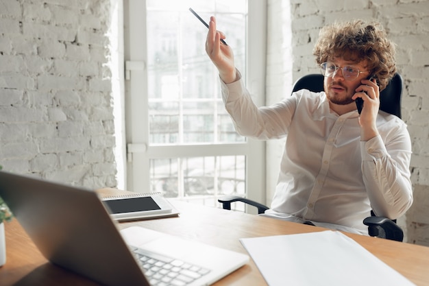 Free Photo talking on phone. caucasian young man in business attire working in office