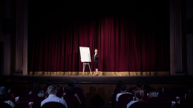 Free photo talking to students. female speaker giving presentation in hall at workshop. business centre. rear view of participants in audience. conference event, training.