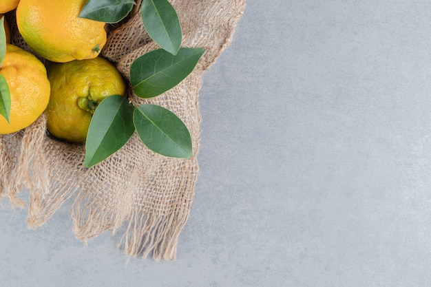 Free photo tangerines bundled on a piece of cloth on marble .