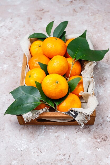 Tangerines (oranges, clementines, citrus fruits) with green leaves on concrete surface with copy space