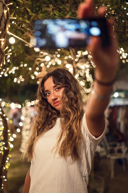 Tanned Caucasian female taking a selfie at an amusement park