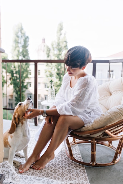 Free photo tanned girl with elegant manicure and pedicure playing with funny beagle dog which resting on carpet