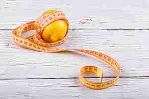 Free photo tape-measure twined around an lemon lying on white floor