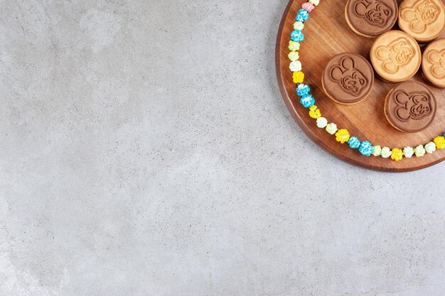 Tart cookies ringed with popcorn candies on a wooden tray on marble background. High quality photo