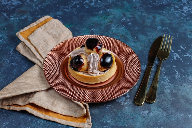 Tart with profiteroles on top with whipped cream.