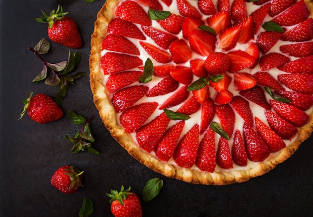 Tart with strawberries and whipped cream decorated with mint leaves. Top view