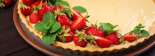 Tart with strawberries and whipped cream decorated with mint leaves