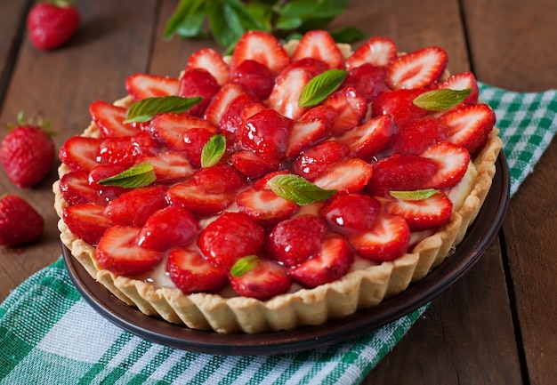 Tart with strawberries and whipped cream decorated with mint leaves