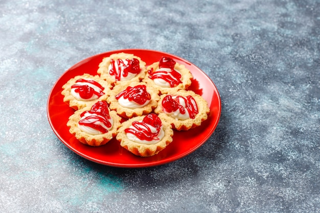 Tartlets with white chocolate filling and berry jam on top.