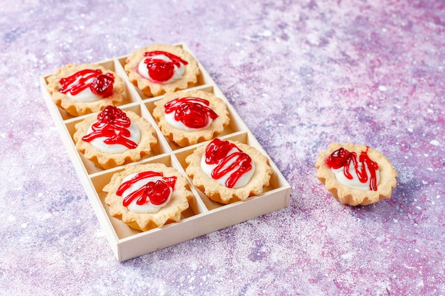 Tartlets with white chocolate filling and berry jam on top.