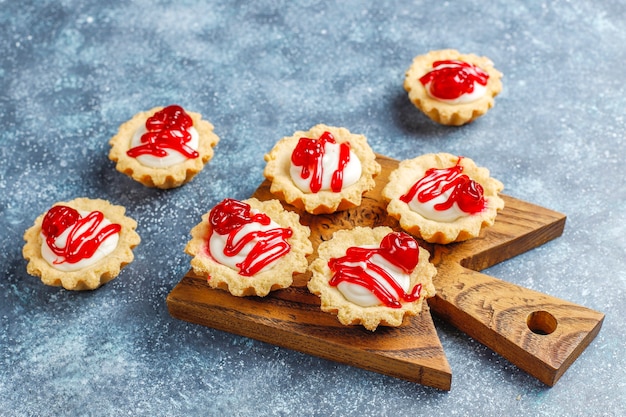 Tartlets with white chocolate filling and berry jam on top.