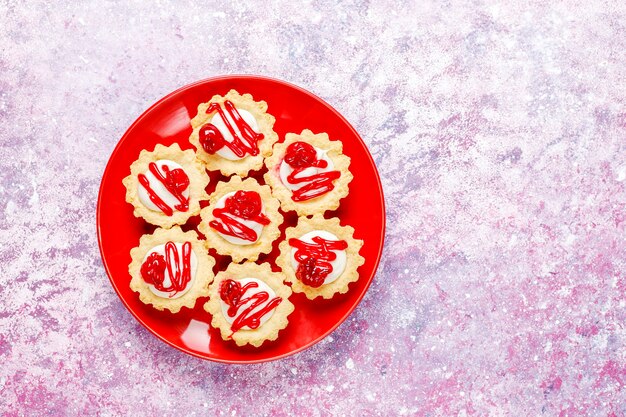 Tartlets with white chocolate filling and berry jam on top.