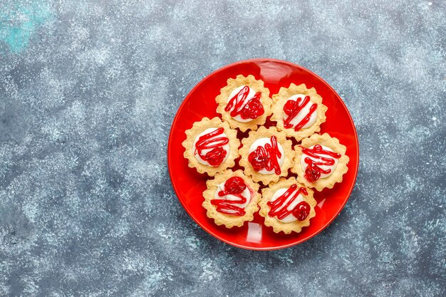 Tartlets with white chocolate filling and berry jam on top.