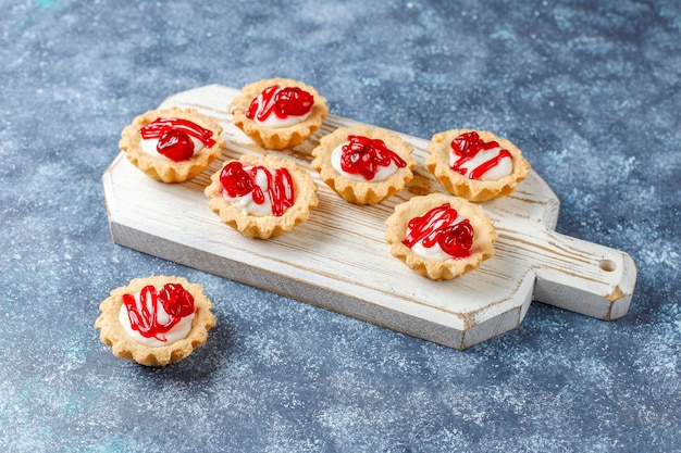 Tartlets with white chocolate filling and berry jam on top.