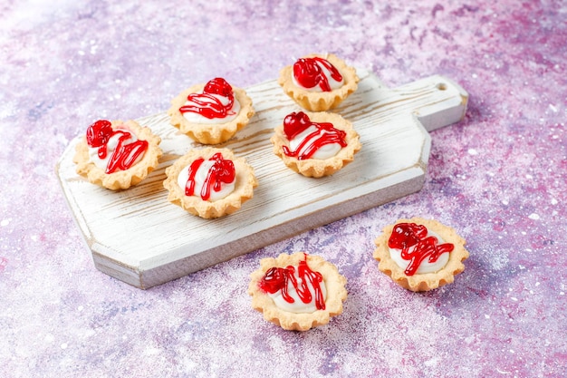 Tartlets with white chocolate filling and berry jam on top.