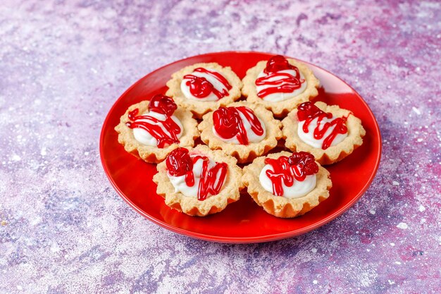 Tartlets with white chocolate filling and berry jam on top.