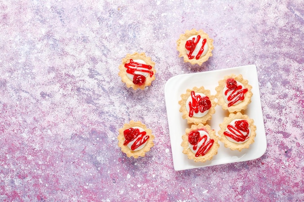 Tartlets with white chocolate filling and berry jam on top.