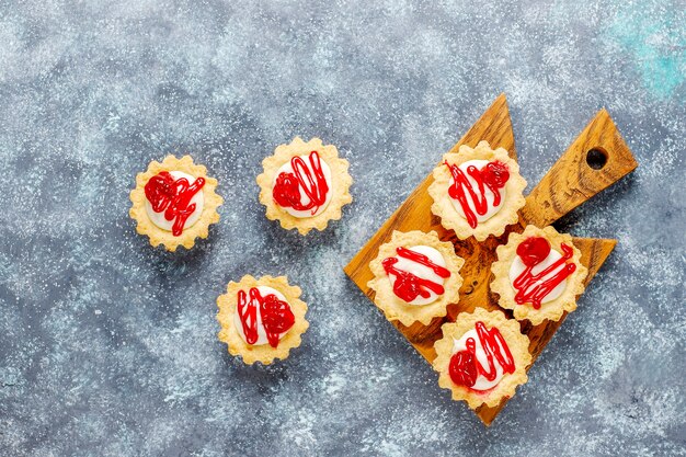 Tartlets with white chocolate filling and berry jam on top.