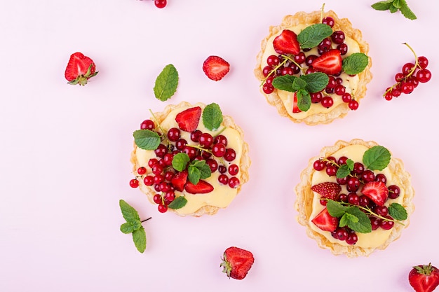 Tarts with strawberries, currant and whipped cream decorated with mint leaves