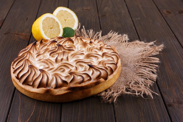 Tasteful lemon pie with white cream served on wooden table