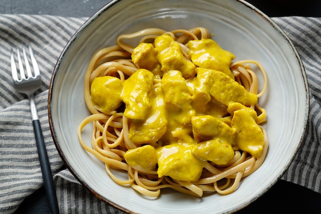 Free photo tasty appetizing noodles spaghetti udon with chicken chunks in curry sauce served on plate. closeup.