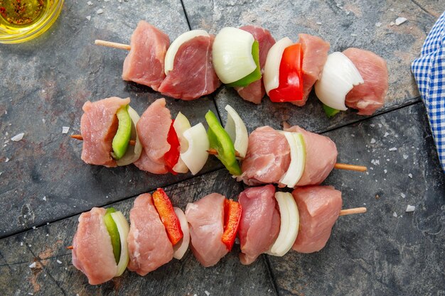 Tasty appetizing raw meat skewers on dark stone background. Closeup