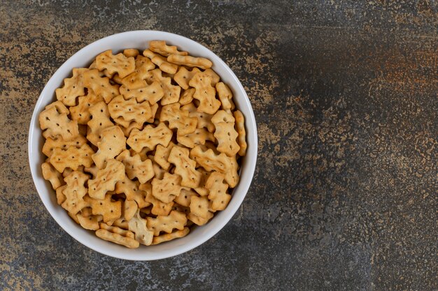 Tasty baked crackers in white bowl.