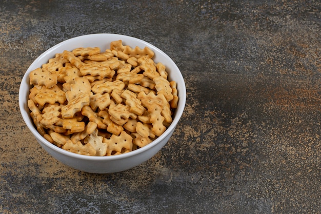 Tasty baked crackers in white bowl.