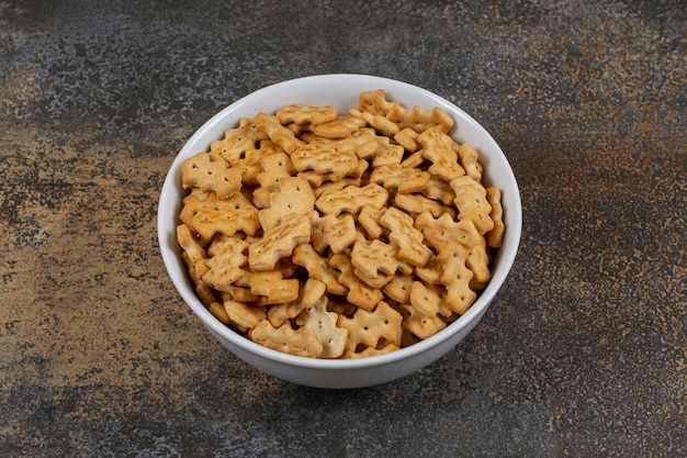 Tasty baked crackers in white bowl.