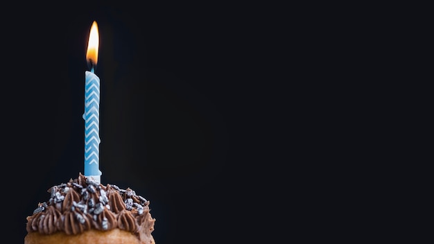 Tasty birthday muffin on black background with copy space