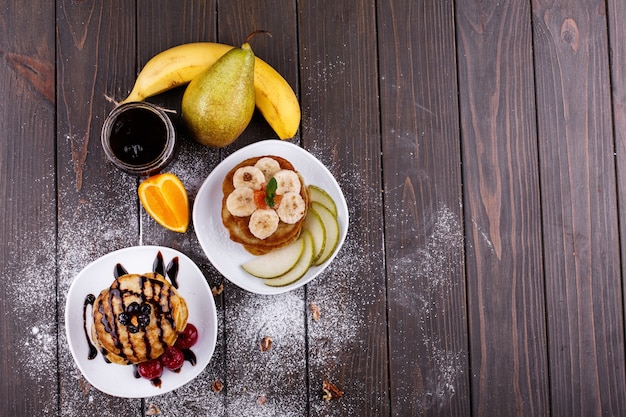 Tasty breakfast. Delicious pancakes covered with chocolate, cherries, bananas and pears