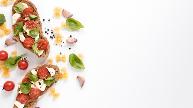 Tasty bruschetta; raw farfalle pasta and fresh ingredients isolated over white background