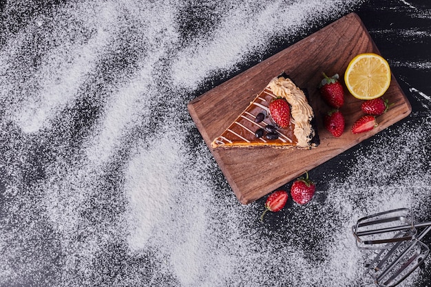 Tasty cake with fruits next to mixer on wooden board. 