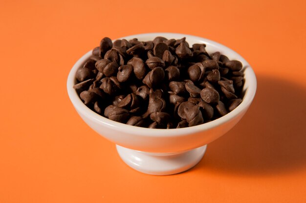 Tasty chocolate chips in bowl high angle