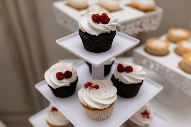 Free photo tasty chocolate cupcakes with raspberry and whipped cream on the candy bar