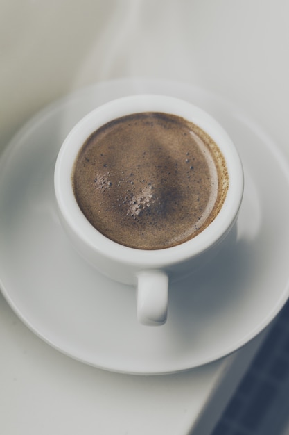 Free Photo tasty coffee espresso in small cup near window. home concept. top view. toning.