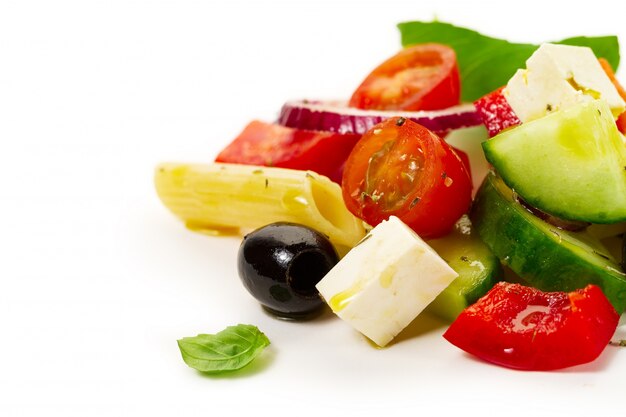 Tasty colorful appetizing ingredients for greek vegetable salad with pasta penne on bright background.