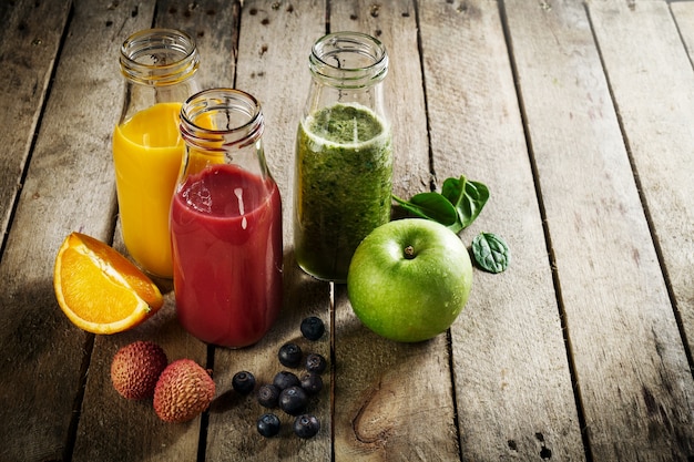 Free photo tasty colorful fresh homemade smoothies in glass jars on wooden table. healthy, detox concept.