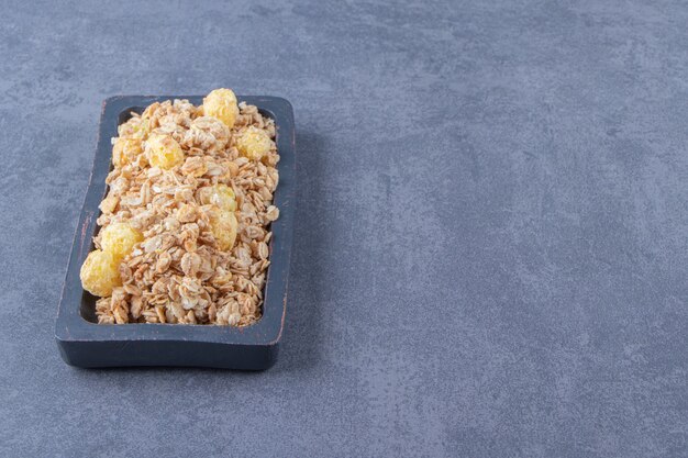 Tasty cornflakes in a board, on the marble table.