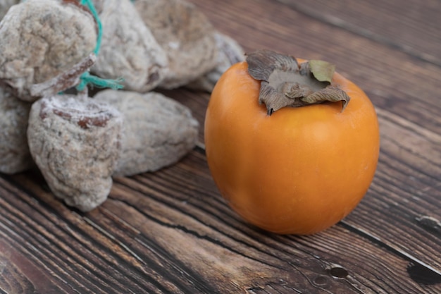 Tasty fuyu persimmon and dried persimmons on wooden surface