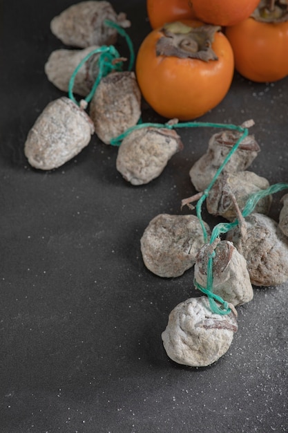 Tasty fuyu persimmons and dried persimmons on black surface