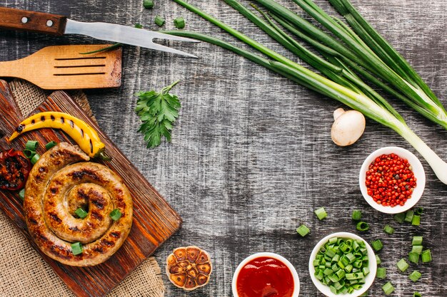 Tasty grilled sausages and fresh vegetable on old backdrop