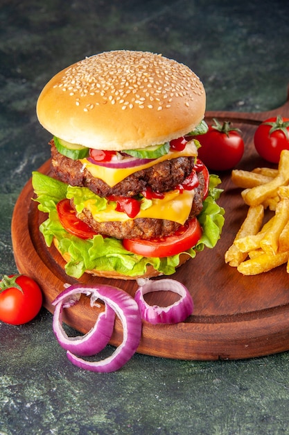 Tasty homemade sandwich tomatoes pepper on wooden cutting board onions tomato with stem fries on dark color surface