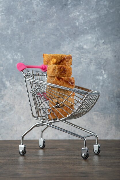 Tasty hot sushi rolls in small trolley on wooden table. 