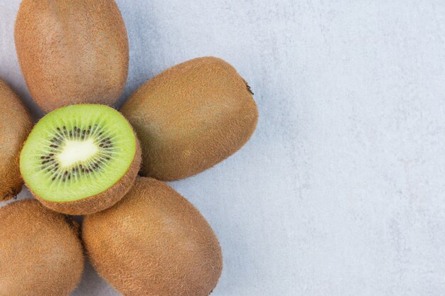 Tasty kiwi fruit, whole and sliced, on the marble table.